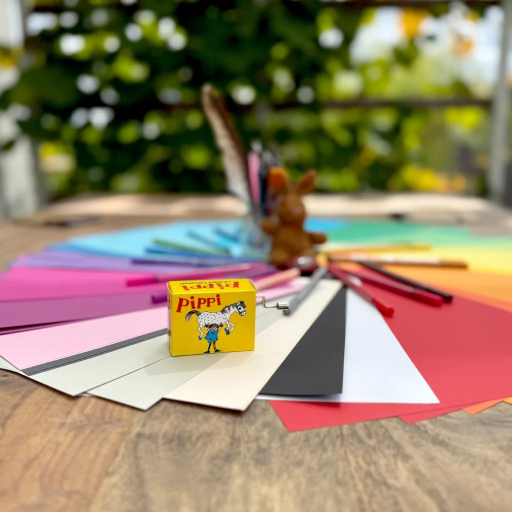 bunte Papiere im Kreis angeordnet mit bunten Stiften und dem Stoffhasen auf einem Tisch